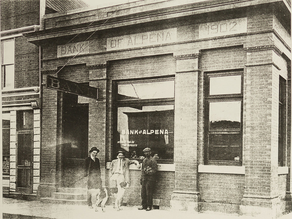 Фотография сделана примерно в 1918 или 1919 году. Карл Т. Айзенбрей - кассир Банка Алпены с 1918 по 1946 годы. Джон Кук (отец Роберта С. Кука) много лет был президентом Банка Алпены. https://www.abt.bank/about/our-history/